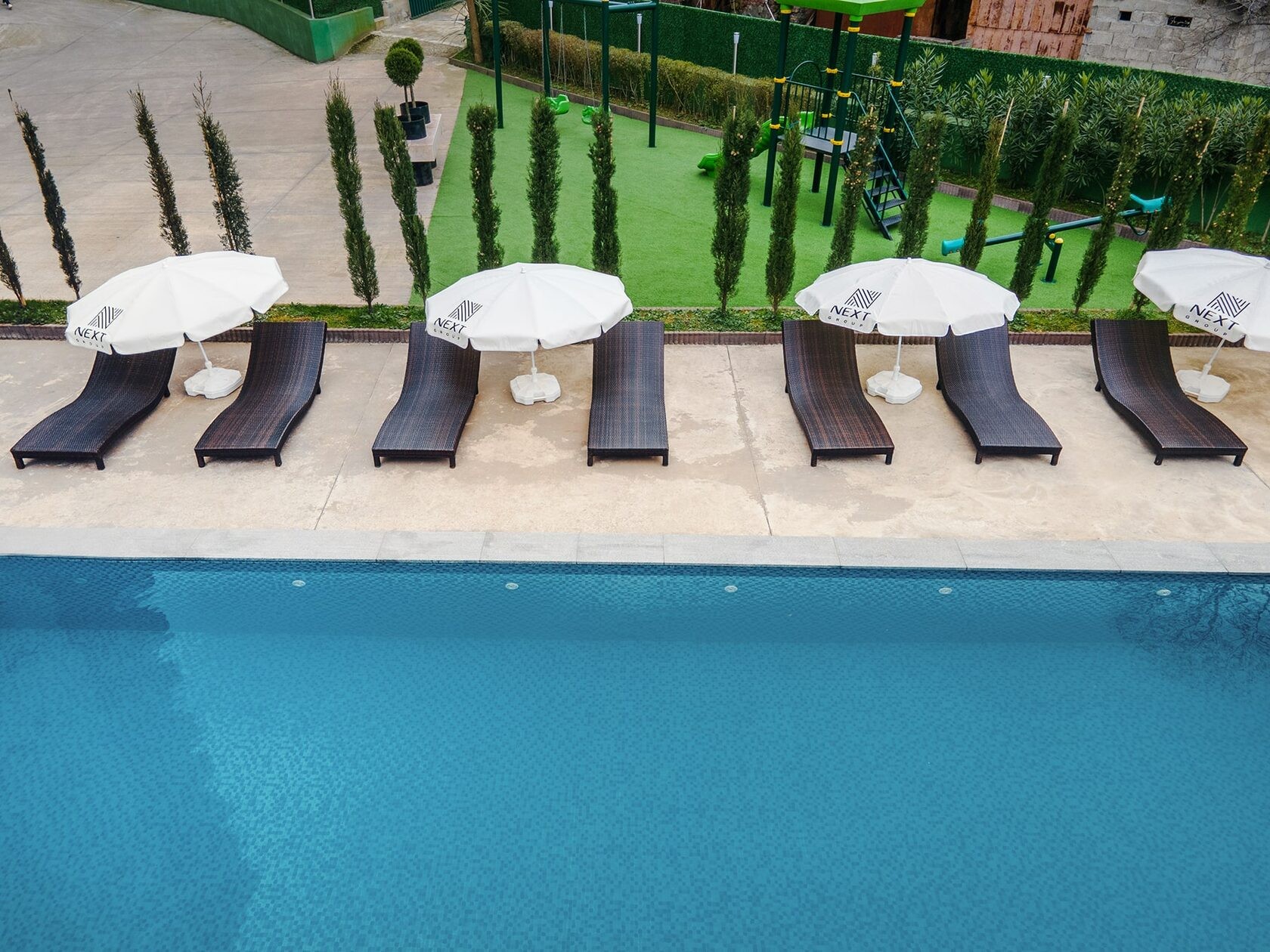 NEXT Green outdoor pool with loungers and garden landscaping